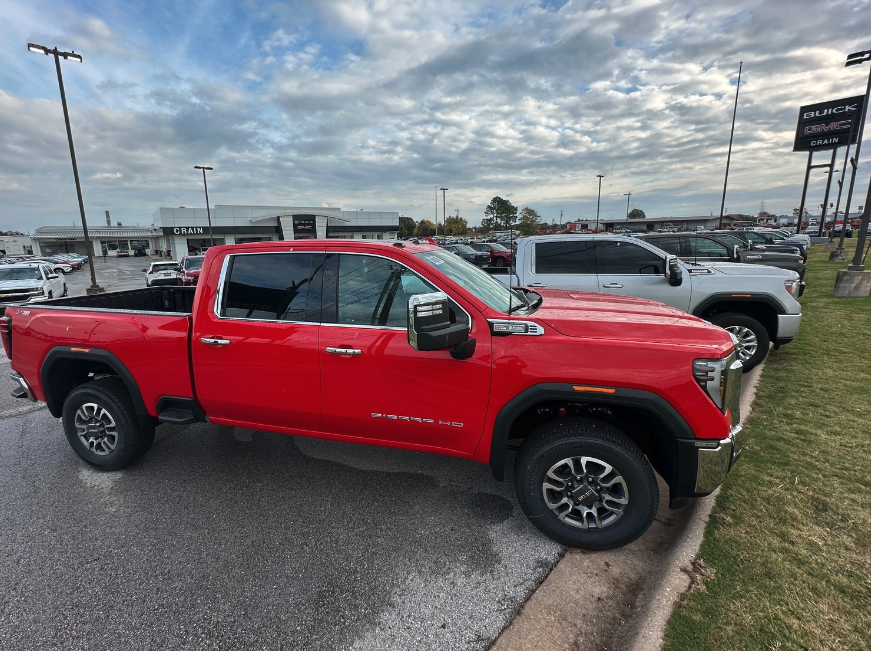 Side profile of a red GMC Sierra HD with Pro Safety Plus parked in front of Crain Buick GMC in Springdale, Arkansas